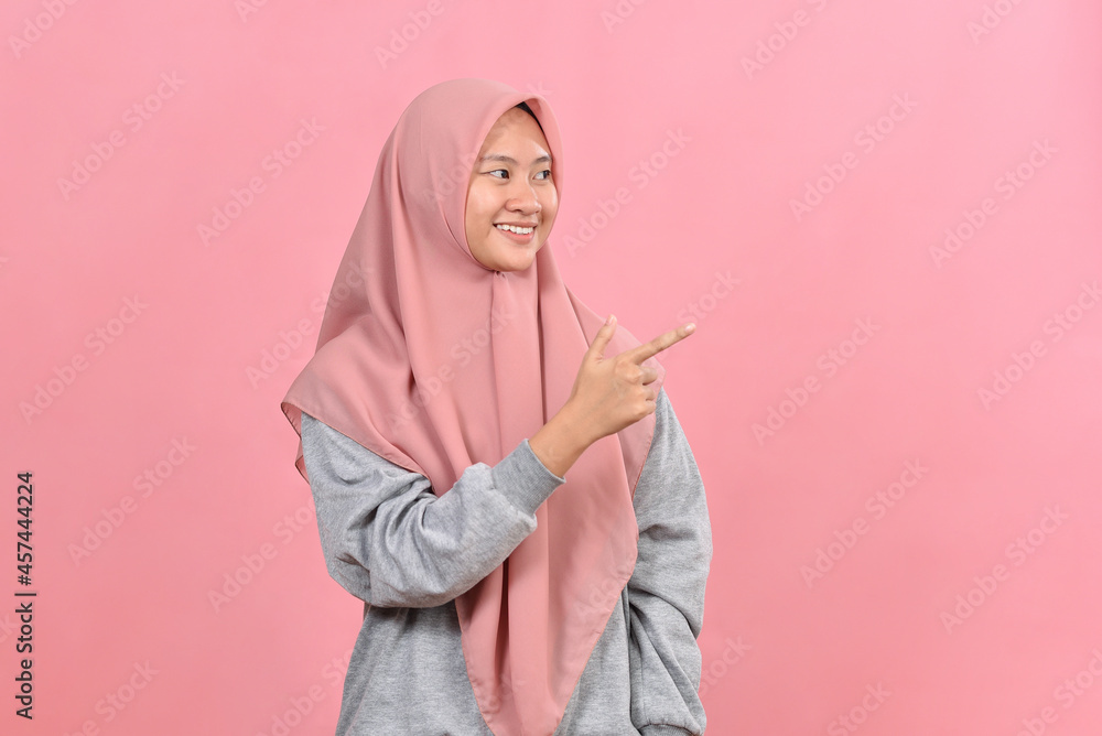 Fototapeta premium Young Asian muslim woman points a copy space