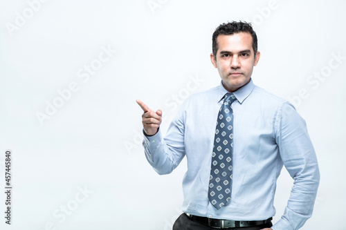 An Asian working man in an office suit is standing pointing with a finger, on white background, with copy space.