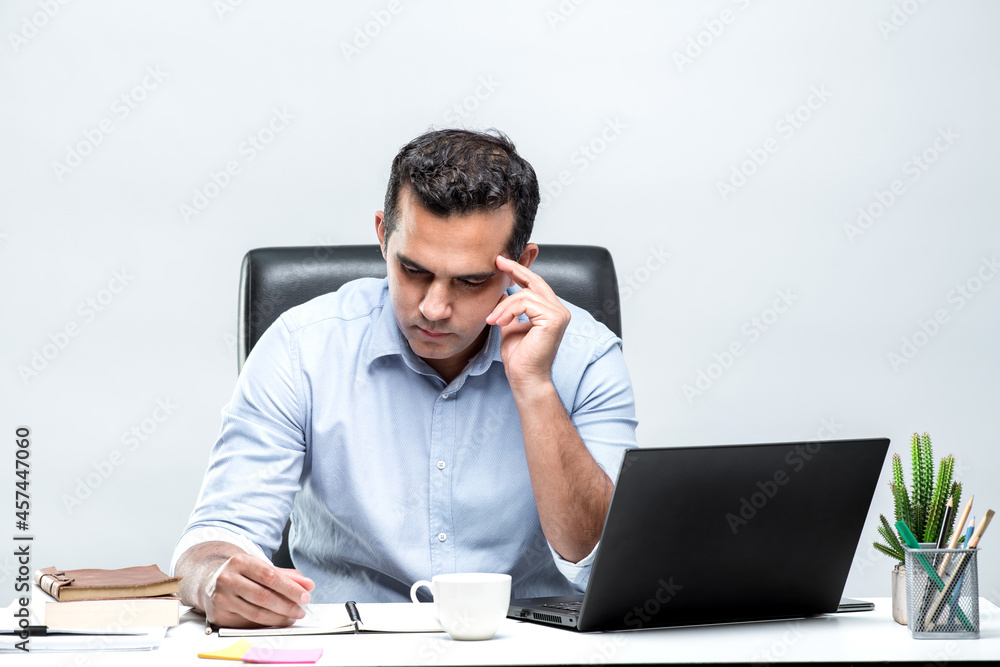 An Asian office worker is sitting in front of a laptop computer at his desk and is having a headache and is not happy to see the work with his documents at the office. An Asian office worker is sitting in front of a laptop computer at his desk and is having a headache and is not happy to see the work with his documents at the office.