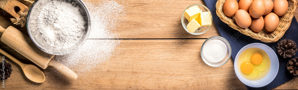 Baking utensils and cooking ingredients for cake bakery include flour, butter, sugar, eggs, and tools on the table, top view with copy space. Baking utensils and cooking ingredients for cake bakery include flour, butter, sugar, eggs, and tools on the table, top view with copy space.