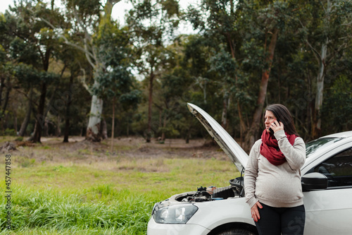 Foto pregnant latina woman talks on phone while waiting for mechanic service to arriv