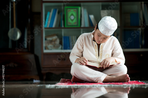 A little Asian Muslim boy is sitting and reading the Quran. The peace in the mosque  with copy space.