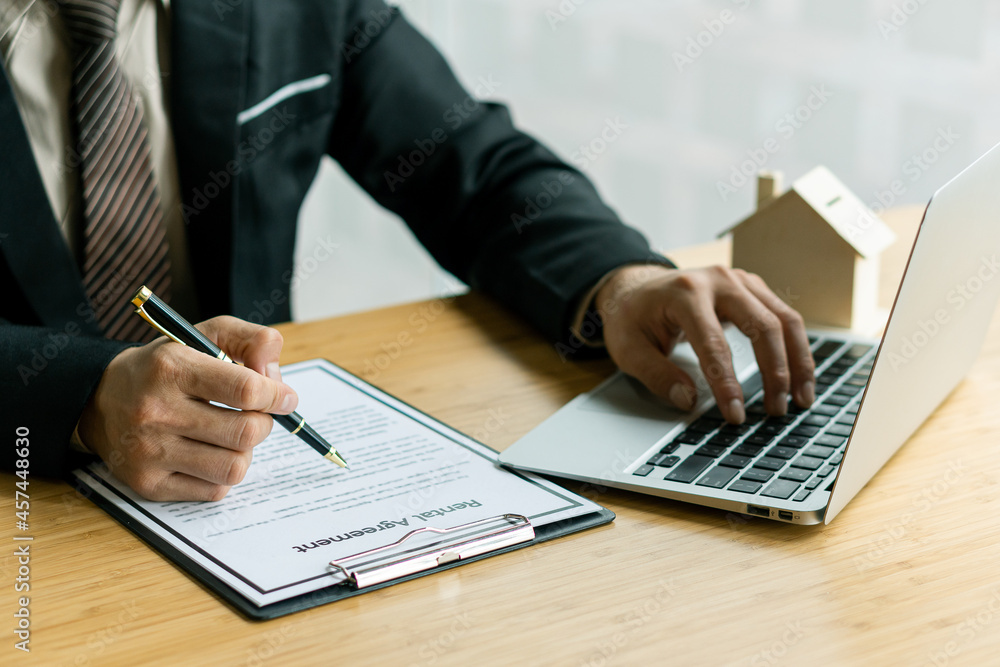 Businessman or home sales representative works with contract documents and calculator with laptop To calculate interest, taxes and profits for sale and rent. Businessman or home sales representative works with contract documents and calculator with laptop To calculate interest, taxes and profits for sale and rent.