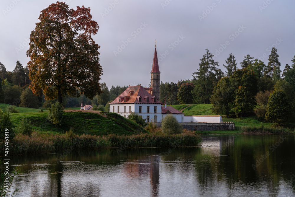 View of the Priory Palace on the shore of the Black Lake on an autumn sunny evening with clouds, Gatchina, St. Petersburg, Russia