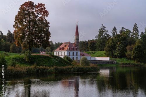 View of the Priory Palace on the shore of the Black Lake on an autumn sunny evening with clouds, Gatchina, St. Petersburg, Russia © Ula Ulachka