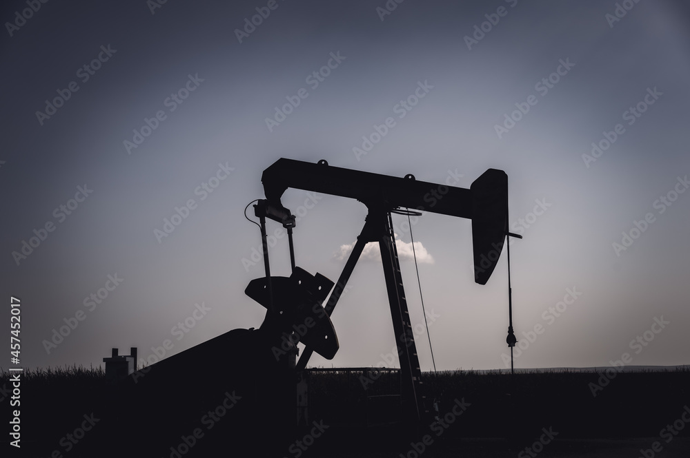 Oil pump jack against an open sky in a rural midwest corn field