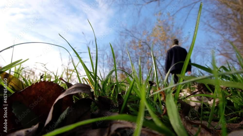 A blurred man person walking in a green grass field with blue sky and staring in deep thought for a moment of relaxation outdoors in rural countryside A blurred man person walking in a green grass field with blue sky and staring in deep thought for a moment of relaxation outdoors in rural countryside