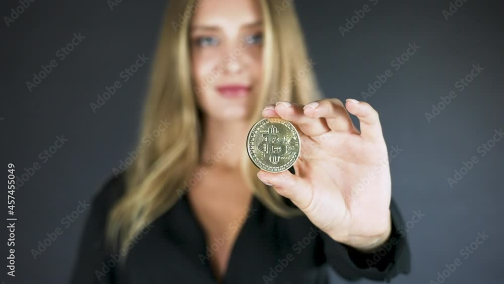 Young blonde woman with closed eyes holding and showing a bitcoin coin. Young blonde woman with closed eyes holding and showing a bitcoin coin.