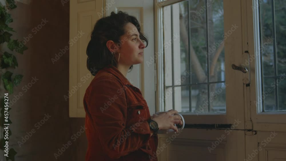 Young woman drinking hot tea and checking the time on her wrist watch, medium shot Young woman drinking hot tea and checking the time on her wrist watch, medium shot