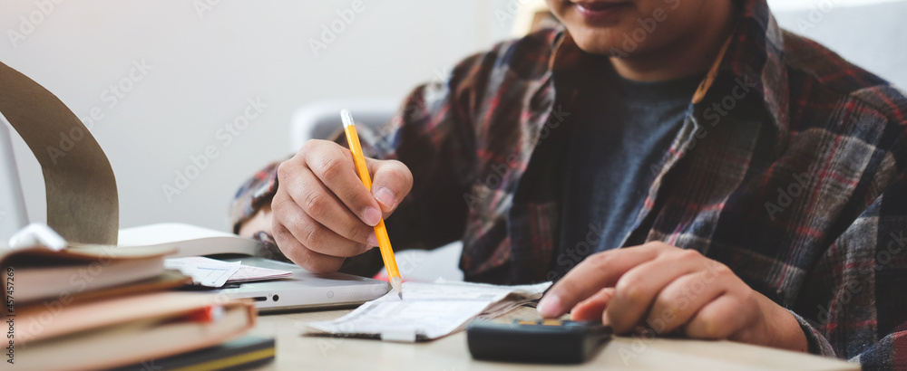Cropped shot Asian man calculating and managing household finances at home. Cropped shot Asian man calculating and managing household finances at home.