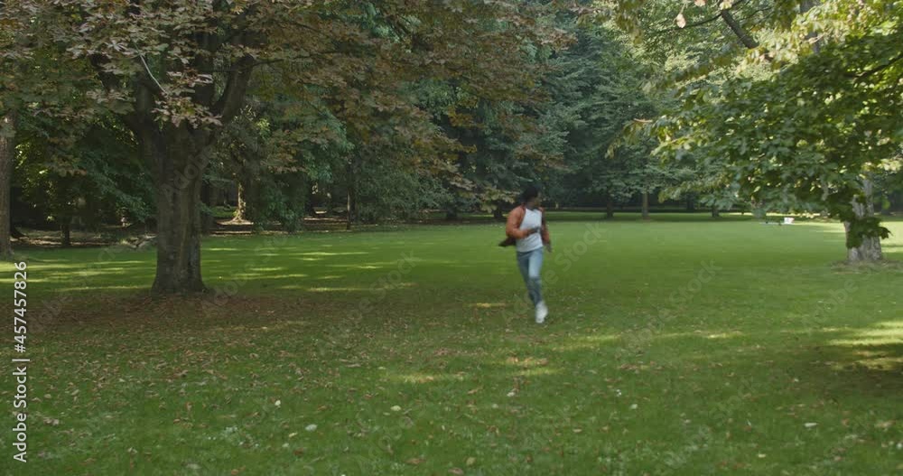 Young black man running scared through a green park Young black man running scared through a green park