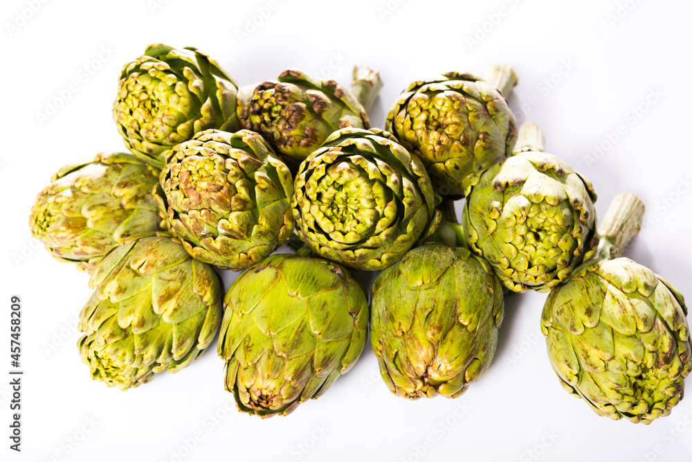 Obraz premium Uncooked green artichokes on a white surface