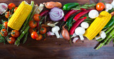 Natural border of vegetarian food objects - fresh vegetables, mushrooms, greens and herbs on wooden table