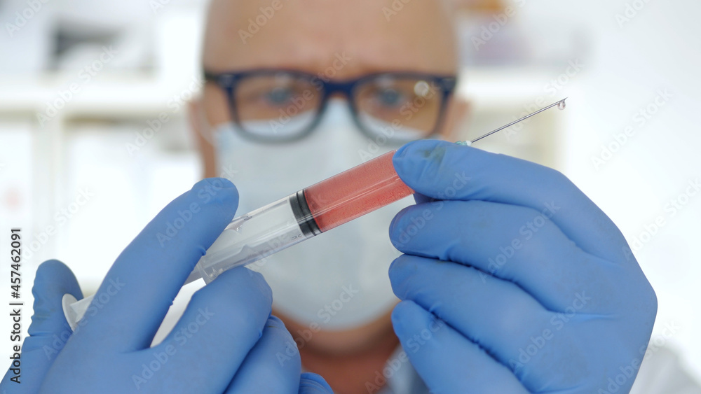 Doctor Wearing Protecting Gloves and Face Mask Keeping in Hand an Injection Doctor Wearing Protecting Gloves and Face Mask Keeping in Hand an Injection