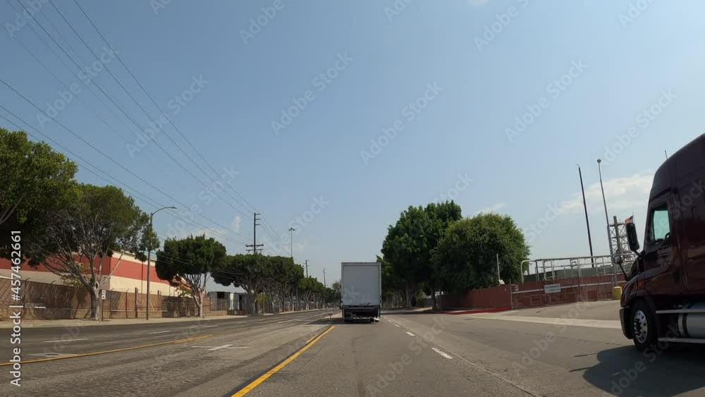 Driving along a city street with industrial neighborhoods on a road lined with trees on a sunny day Driving along a city street with industrial neighborhoods on a road lined with trees on a sunny day