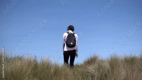 A woman wearing a black cap and a black backpack is walking on the moorlands of Ecuador in Rucu Pichincha near Quito. photo