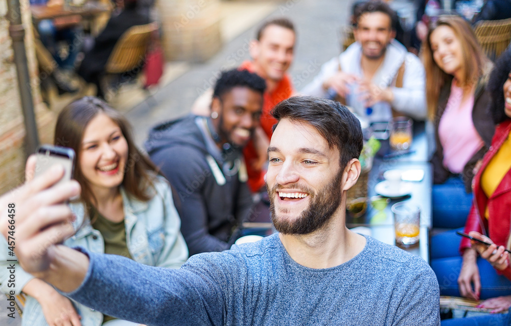 Happy man taking selfie while young people having fun together at coffee bar Happy man taking selfie while young people having fun together at coffee bar