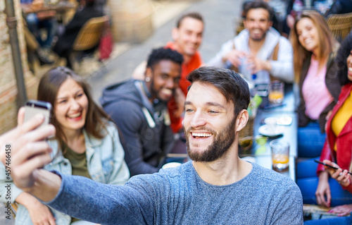 Happy man taking selfie while young people having fun together at coffee bar