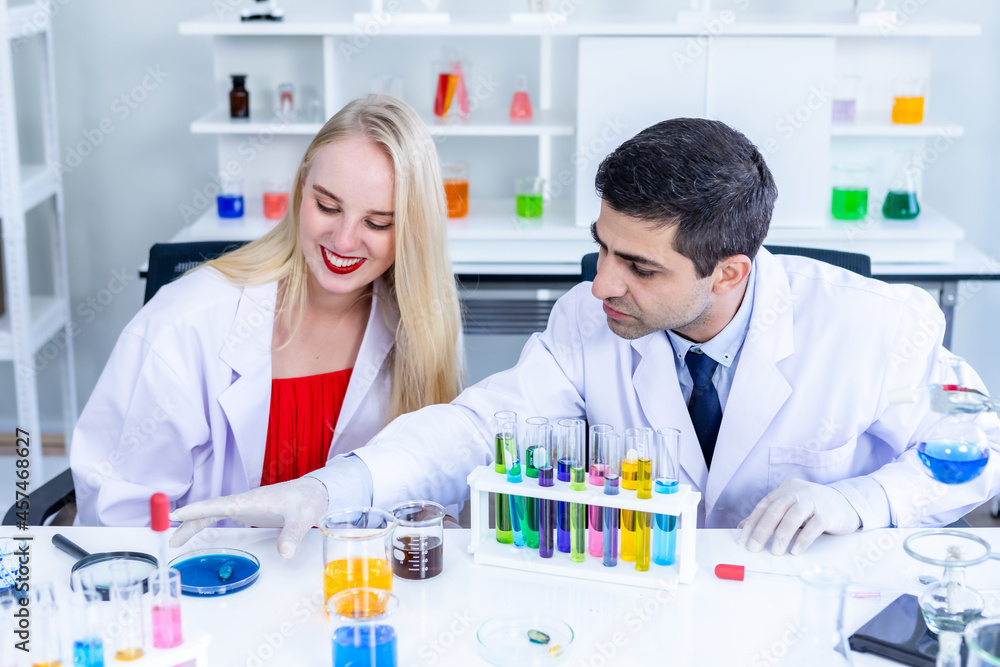 Two scientists are working holding looking at test tube with sample in a chemistry lab scientist or young female and male researcher are doing investigations in Laboratory analysis background Two scientists are working holding looking at test tube with sample in a chemistry lab scientist or young female and male researcher are doing investigations in Laboratory analysis background