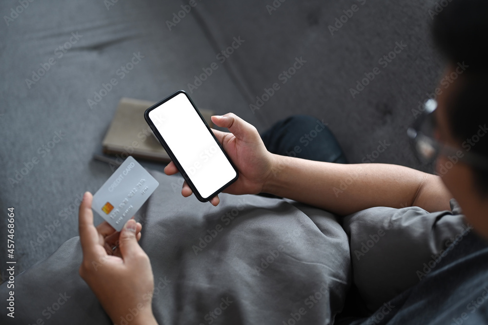 Asian man holding credit card and using smart phone for shopping online or banking online. Asian man holding credit card and using smart phone for shopping online or banking online.