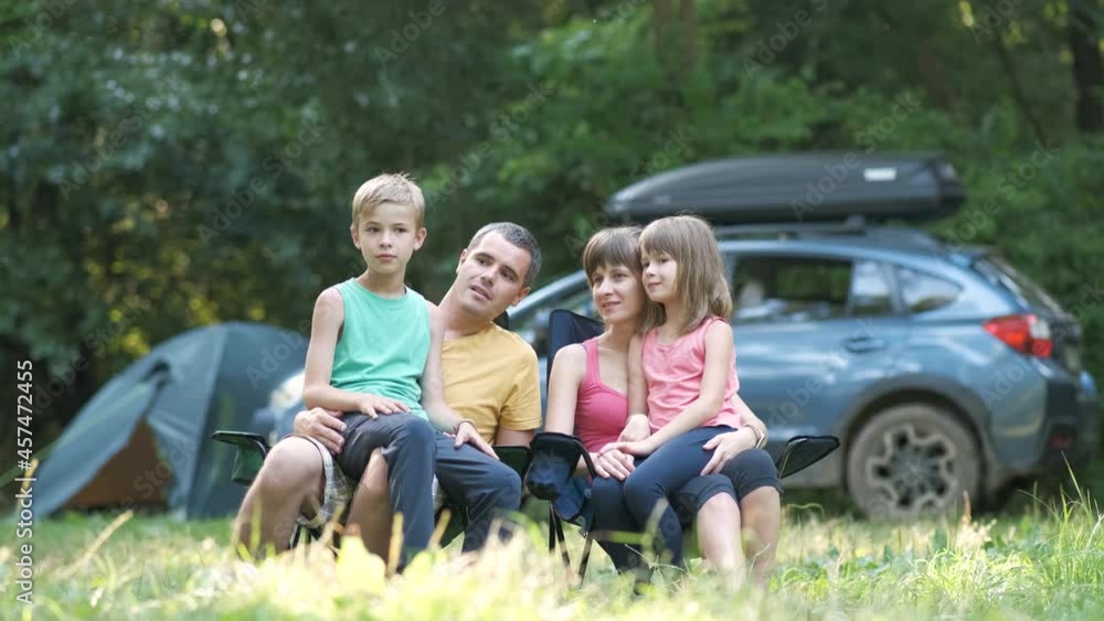 Parents and two kids resting together and talking happily. Happy young family spending time at capmsite outdoors.