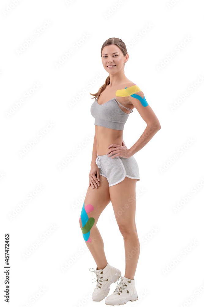 Physio tapes applied to the body of a young athletic woman isolated on white. Physiotherapy, kinesio taping, kinesiology and recovery treatment concepts. Physio tapes applied to the body of a young athletic woman isolated on white. Physiotherapy, kinesio taping, kinesiology and recovery treatment concepts.