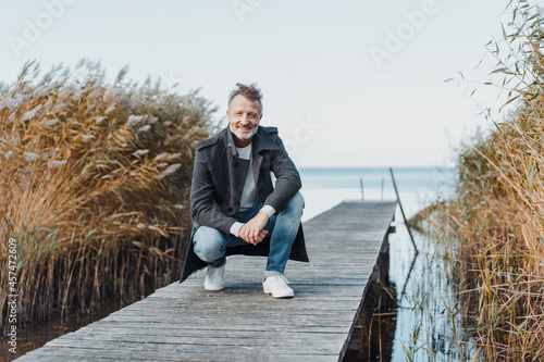 Bilde på lerret Athletic senior man crouching on an old wooden jetty