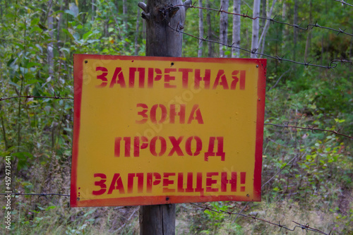 Notified area sign. Sign 'Restricted area. No entry 'hanging on a barbed wire fence in the forest.