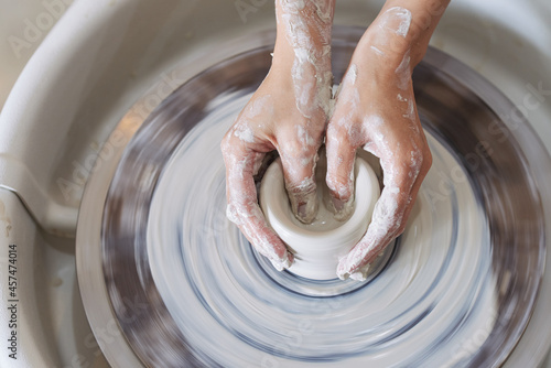 Fotografie Hands of ceramist modelling vase on potters wheel, view from the top