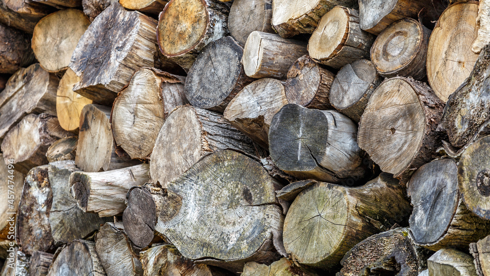 Background of hewed smooth wooden logs. Cut wood texture. Pile of chopped fire wood prepared for winter Background of hewed smooth wooden logs. Cut wood texture. Pile of chopped fire wood prepared for winter