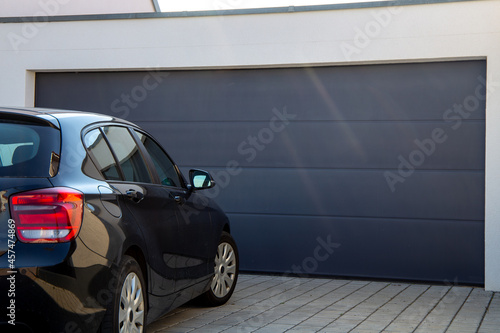 Modernes schwarzes Garagentor mit davor parkendem PKW