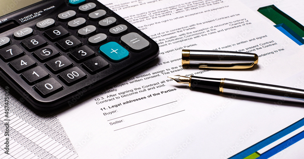 On the desktop there are reports, a calculator and a fountain pen. Workplace close-up. Business concept On the desktop there are reports, a calculator and a fountain pen. Workplace close-up. Business concept