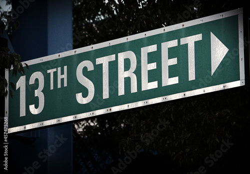 Green Illuminated street sign pointing right to 13th Street in Omaha, Nebraska with dark background