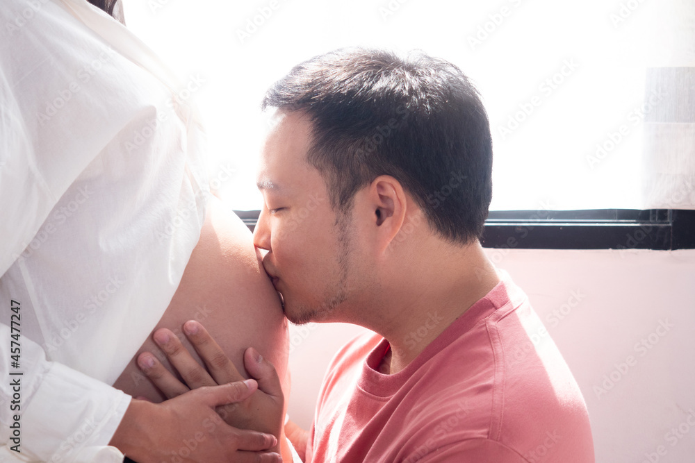Close up. Husband kissing newborn through wife belly and smiling. Concept of healthy for pregnancy people in family. Close up. Husband kissing newborn through wife belly and smiling. Concept of healthy for pregnancy people in family.