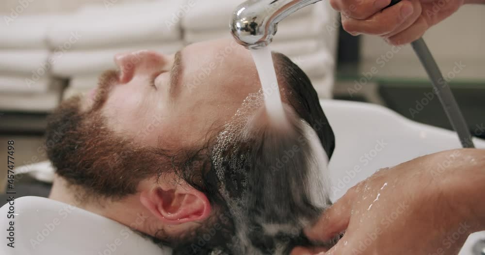 A professional beauty salon worker washing customer hair with water A professional beauty salon worker washing customer hair with water