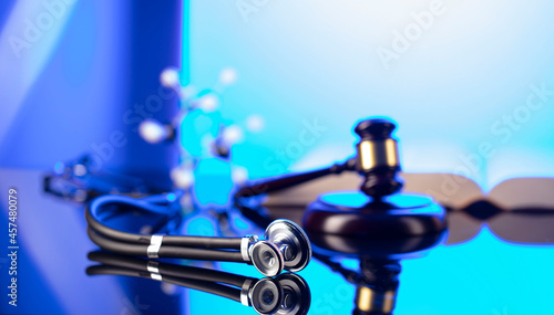 Medical law concept. Gavel  Themis  legal code and stethoscope on the glass table. Blue light.