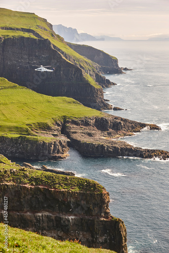 Helicopter flying over mykines atlantic cliffs in Faroe islands. Transportation photo