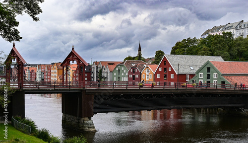 Bridge in front of typical colorful scandinavian buildings on a river in Trondheim in a cloudy rainy day