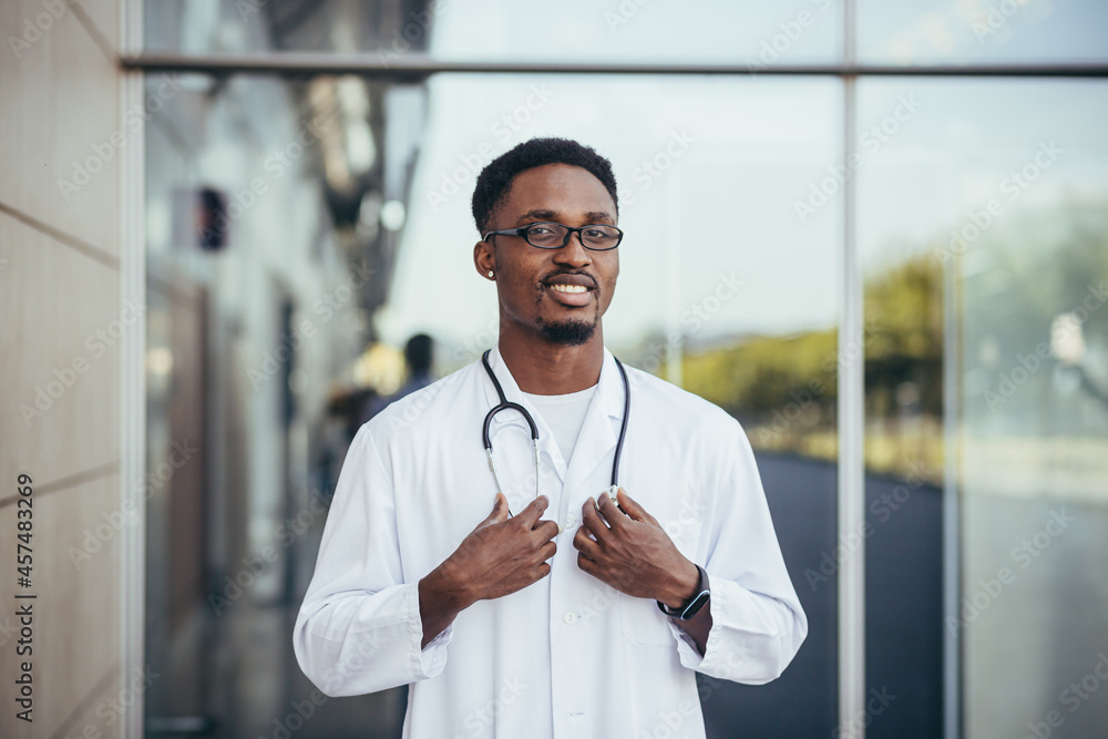 Obraz premium Portrait of an African doctor looking at camera and smiling in front of clinic