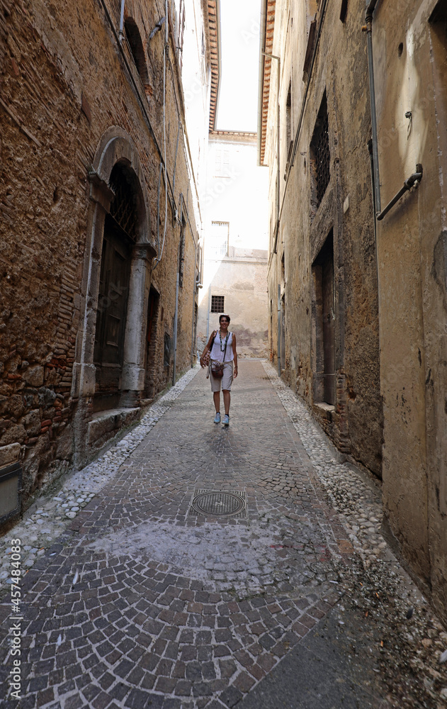 tourist woman walking through the narrow alleys of the ancient city in Italy in summer tourist woman walking through the narrow alleys of the ancient city in Italy in summer