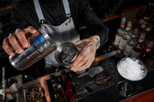 barman is making cocktail with steel shaker photo