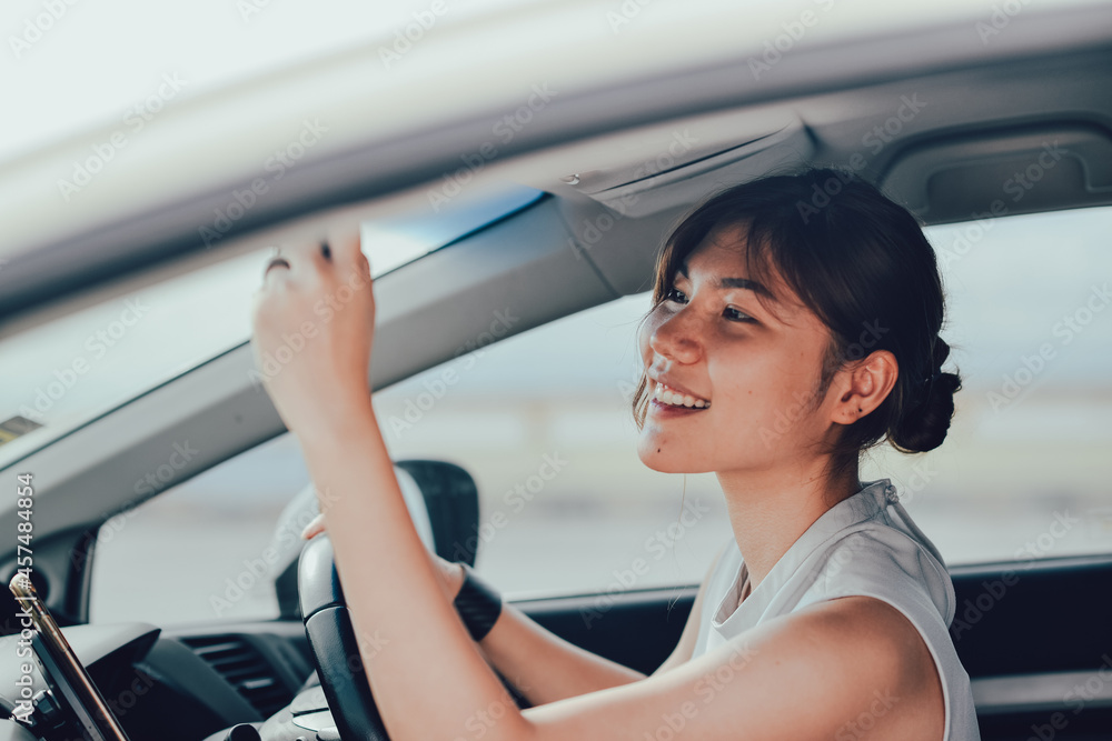 Relaxed asisn woman smiling looking in rear view mirror. siting on the car. lifestyle and people concept. Relaxed asisn woman smiling looking in rear view mirror. siting on the car. lifestyle and people concept.