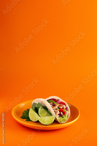 Photos Mexican tacos on orange plate and background