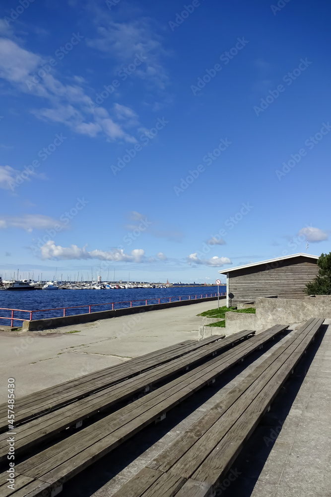 Wood from wooden benches to Pirita river coming into the sea. Seaview with yachts and boats on a dock on a sunny day with blue sky. Pirita, Tallinn, Estonia, Europe. September 2021