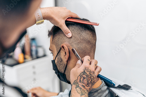 Barber shaving the hair of a man using a razor in a barber shop