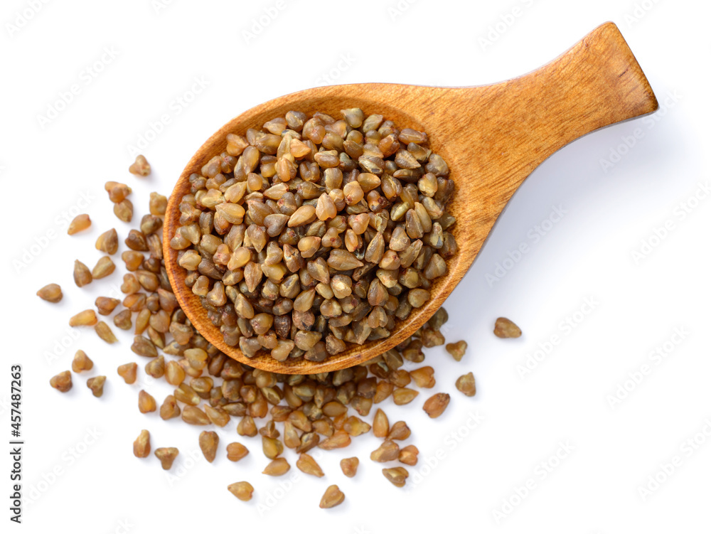 uncooked buckwheat in the wooden spoon, isolated on the white background, top view uncooked buckwheat in the wooden spoon, isolated on the white background, top view