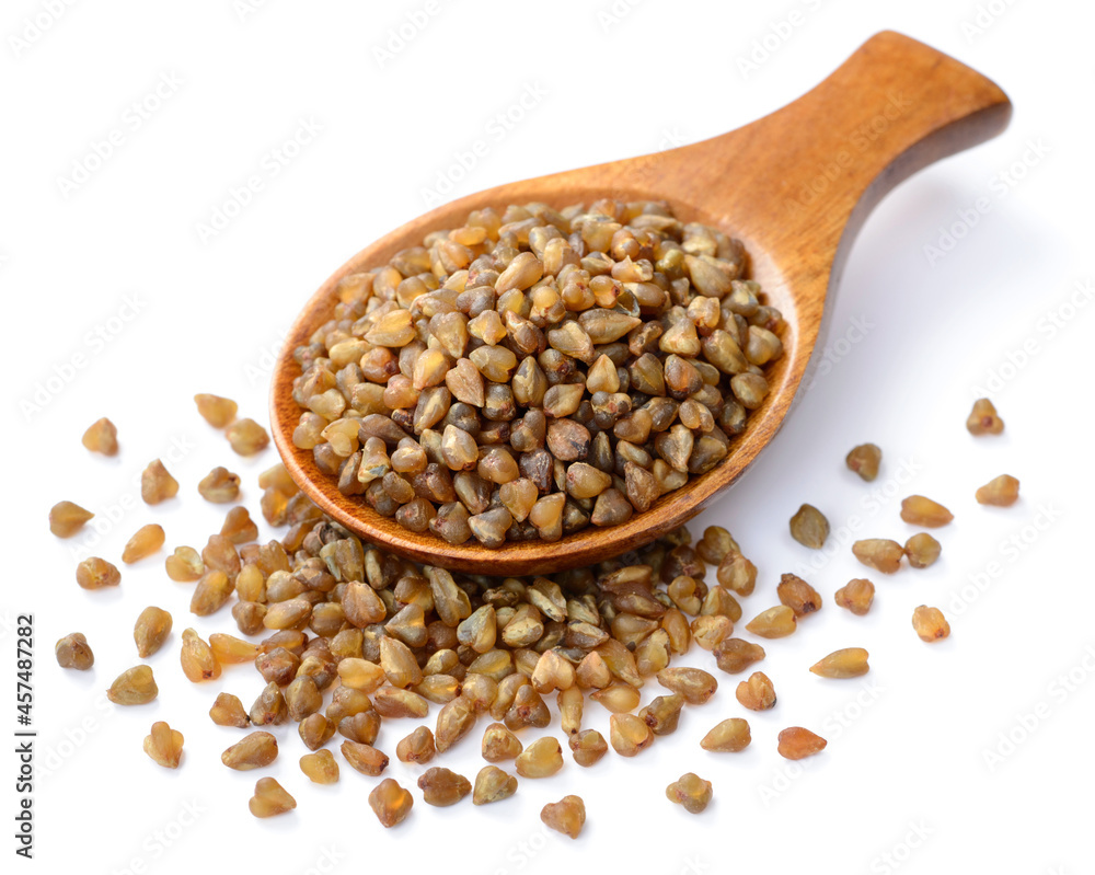 uncooked buckwheat in the wooden spoon, isolated on the white background uncooked buckwheat in the wooden spoon, isolated on the white background
