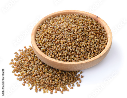 uncooked buckwheat in the wooden plate, isolated on the white background