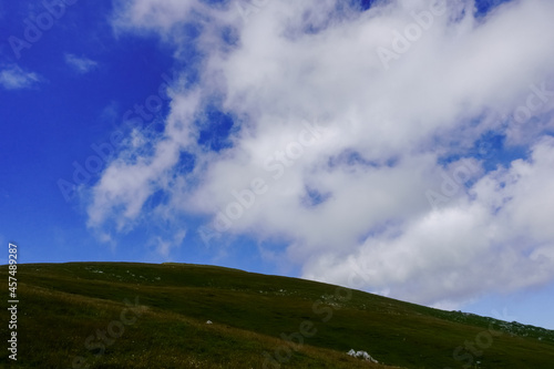 round hill with grass on a mountain with wonderful clouds on the sky
