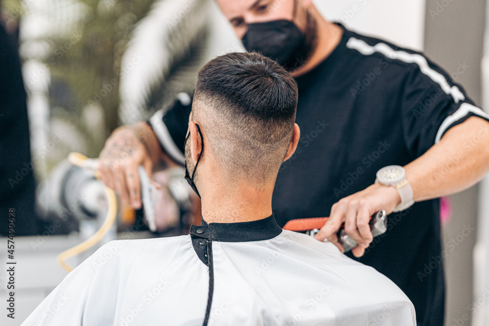 Fototapeta premium Selective focus on the shaved nape of a man with mask in a barbershop
